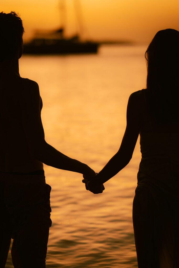 Tiefe Verbindung in der goldenen Stunde – Paar hält sich an den Händen im Wasser bei Sonnenuntergang, Symbol für Einheit und Seelenliebe