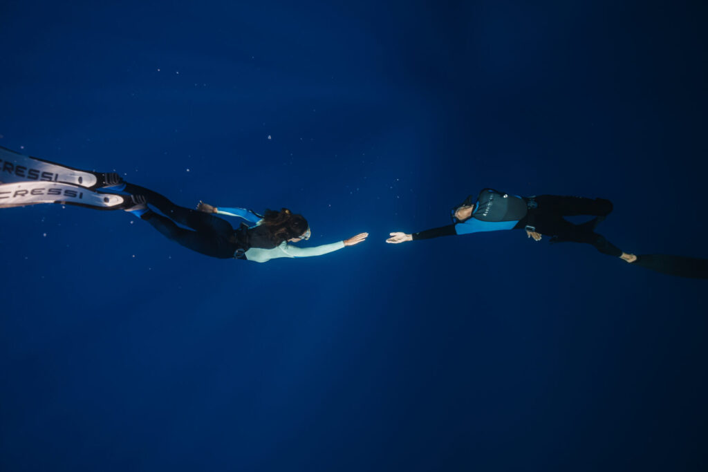 neue Welt leben – Verbindung in Tiefe – Zwei Menschen berühren sich unter Wasser, Ausdruck von Vertrauen, Einheit und innerer Wahrheit