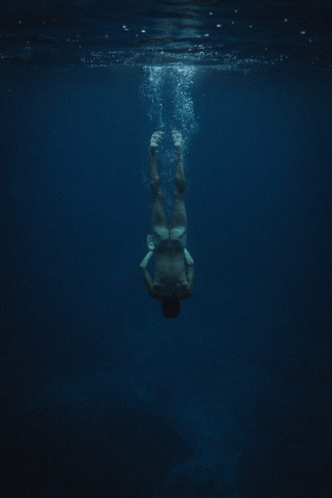 Ehre den Schmerz in der Tiefe: Taucher sinkt in blaues Wasser und findet stille Einsicht und emotionale Erneuerung