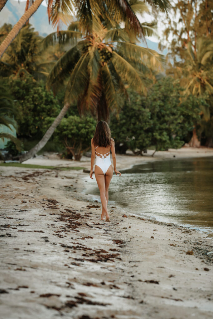 Frau im Badeanzug geht barfuß am Strand entlang – natürliche Weiblichkeit, Rückverbindung zur Erde und Freiheit im Körper.