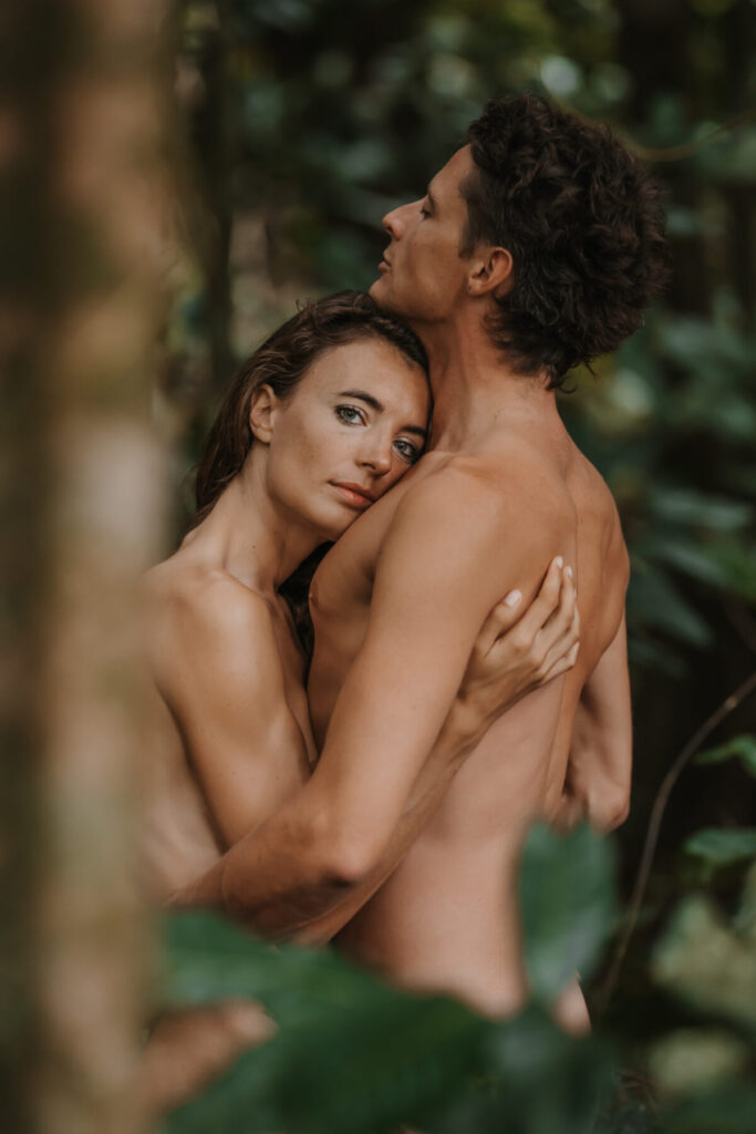 Innige Umarmung im Dschungel – Paar steht nackt und verletzlich beieinander, Ausdruck von Vertrauen, Heilung und tiefer Liebe ohne Streit