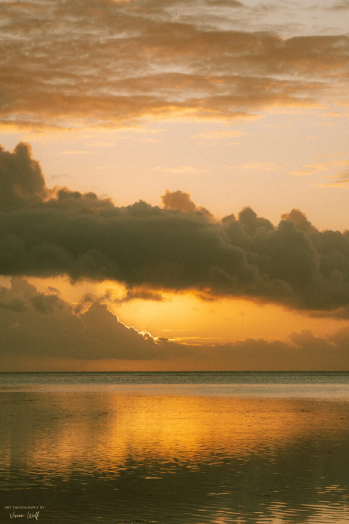Stille Sehnsucht: Sanfte Dämmerung am Meer, goldene Wolken spiegeln sich im ruhigen Wasser.