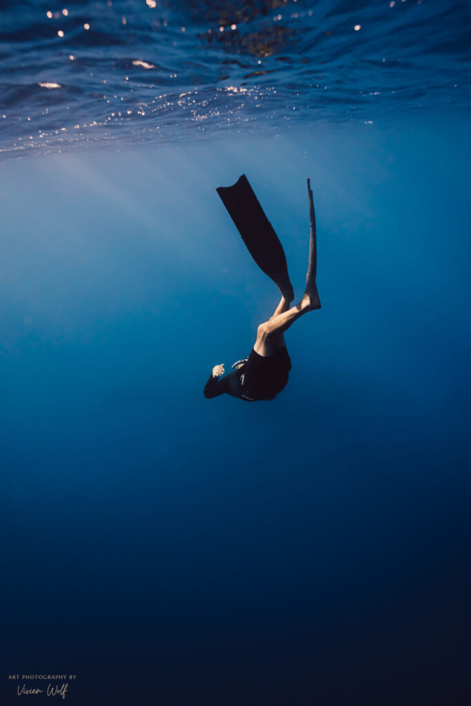klare Entscheidung – Freediver sinkt ins Blau, Zentrierung durch ruhige Atmung als Halt in emotionalen Prozessen.