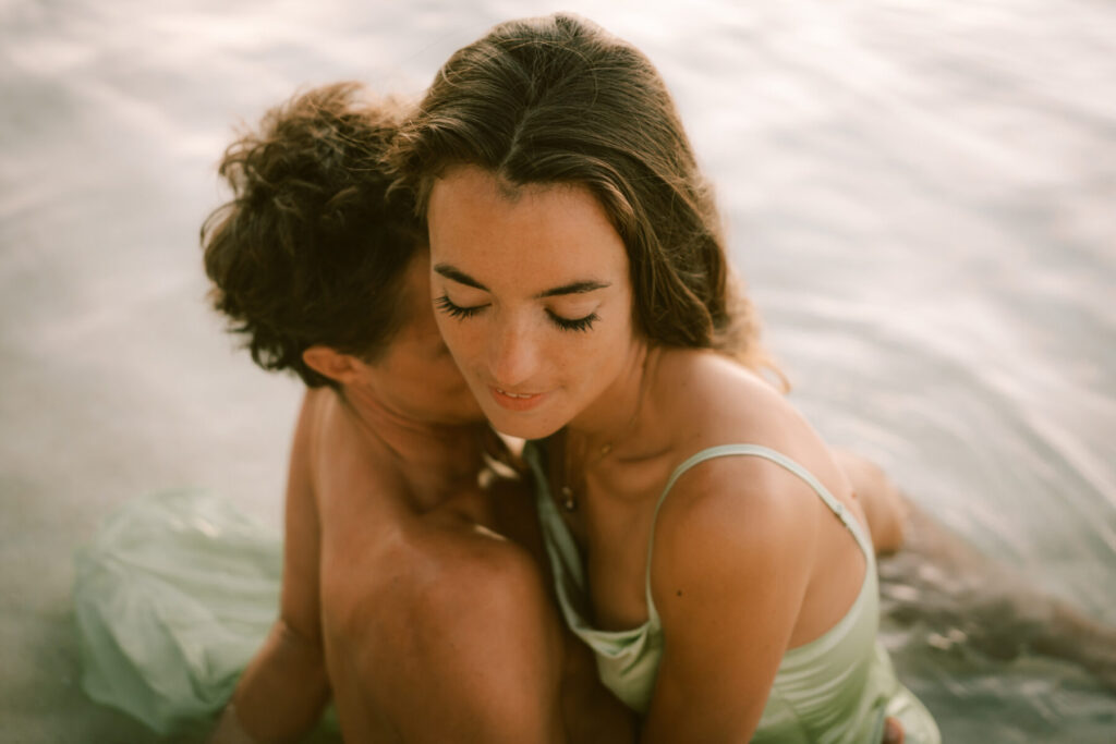 Ein Paar umarmt sich sanft im Wasser, Ausdruck von Frieden, Vertrauen und Hingabe – Sinnbild für die Botschaft des Artikels Liebe ist.