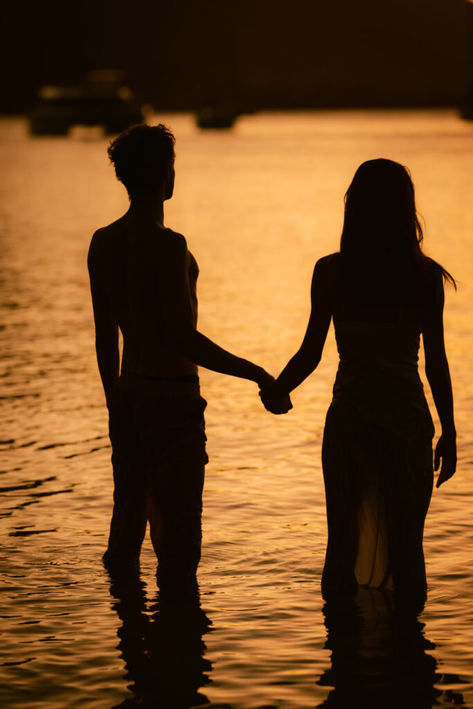 Paar bei Sonnenuntergang Hand in Hand im Wasser – Ausdruck von Nähe, Verbindung und innerer Klarheit für magnetisches Wachstum auf Instagram