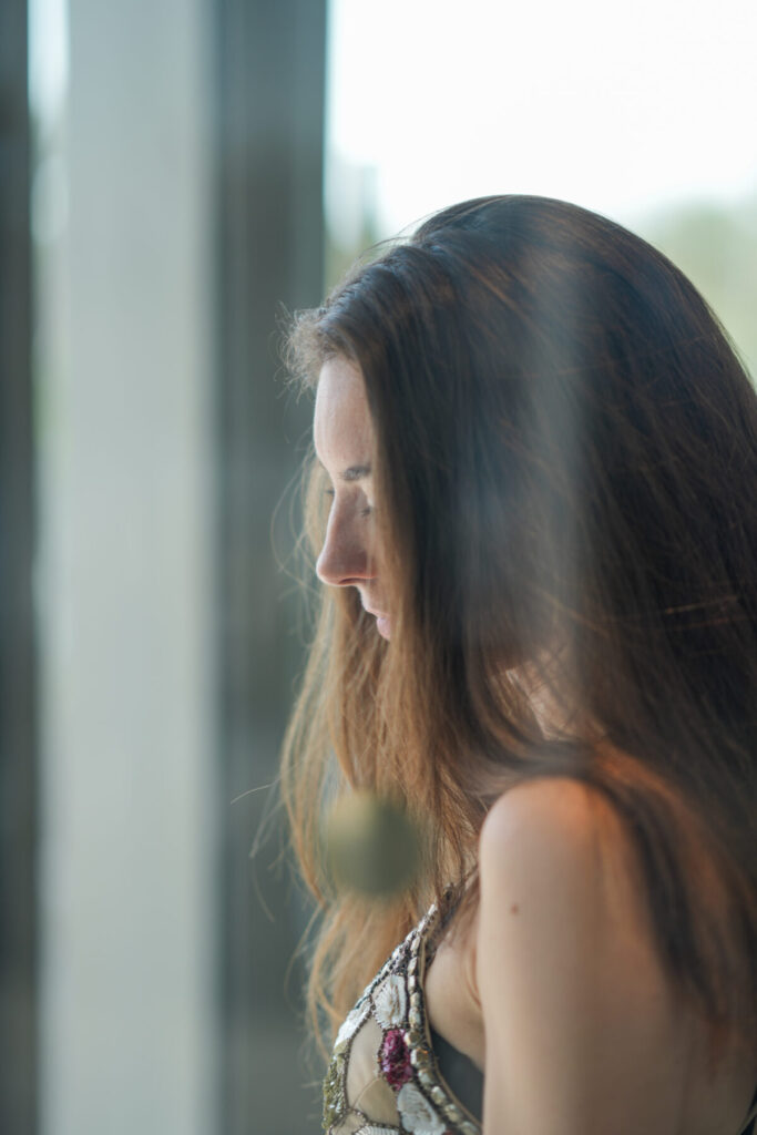 tiefes Erwachen – Frau am Fenster atmet bewusst ein und erlebt durch Breathwork radikale Transformation ins Hier und Jetzt.