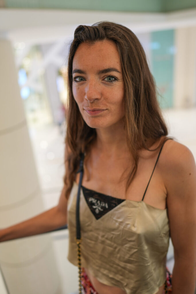 Intime Stille wählen – Frau mit hellem Top in hellem Raum, ruhiger Blick in die Kamera und sanfte, friedvolle Atmosphäre.