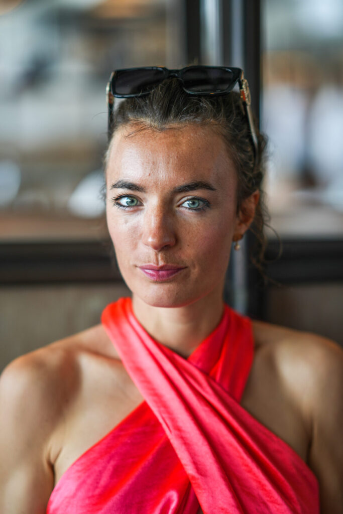 Human Design nicht verstehen: Frau im roten Top mit fragendem Blick im Café, symbolisiert das weitverbreitete Unverständnis für Human Design
