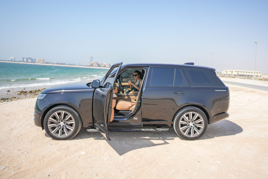 Wahl im Paradies treffen – Frau steigt barfuß aus schwarzem Luxusauto direkt am Strand, Symbol für Freiheit, Reichtum und bewusste Entscheidung