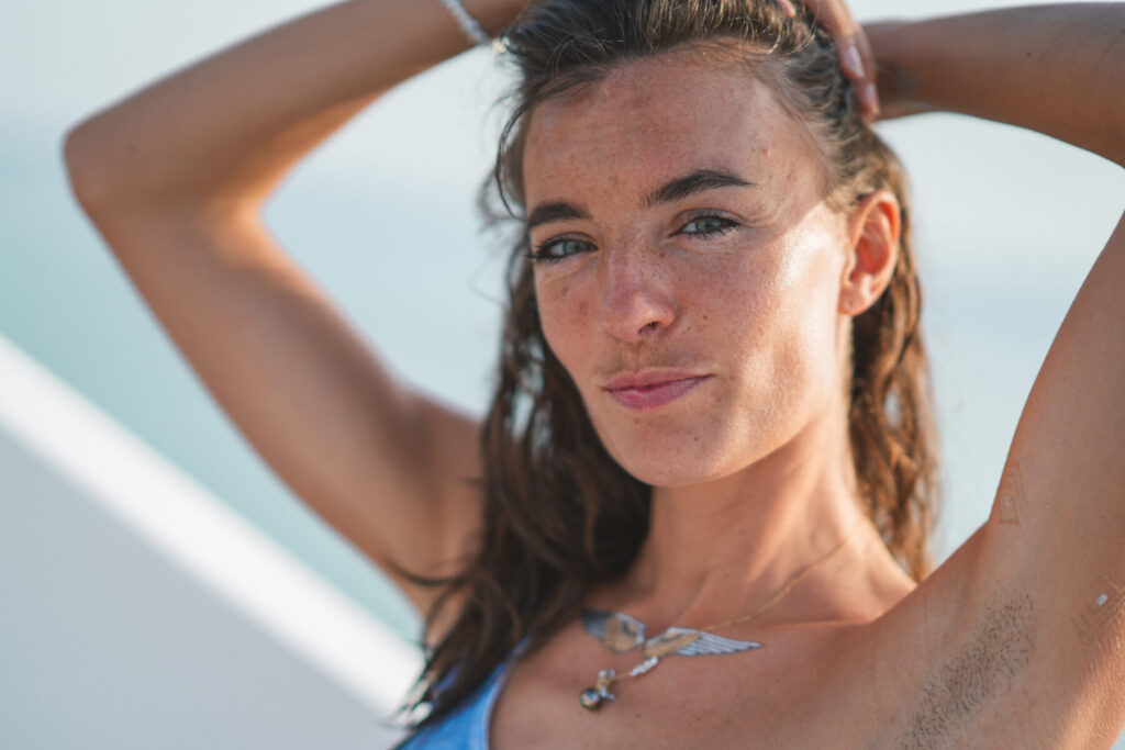 Weichheit im Bewusstsein – Frau auf Boot mit lockerem Blick, Sonnenlicht auf Haut, Symbol für Annahme, Schönheit und Authentizität