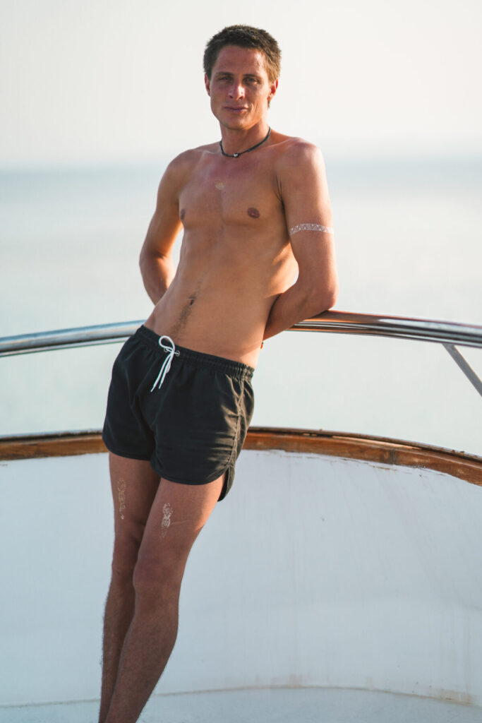 THE ONE verkörpern – Mann in Shorts auf Boot, Rückenansicht im Licht, Ruhe, Kraft, Aufgerichtetsein, Präsenz jenseits der Polarität