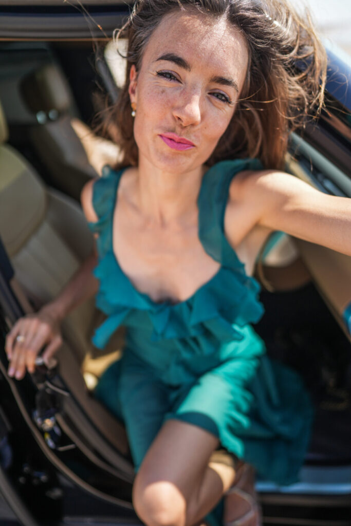 Schritte ins Neue wagen – Frau im türkisgrünen Kleid steigt aus dem Auto, Bewegung, Lebensfreude und Aufbruch in eine neue Zeit