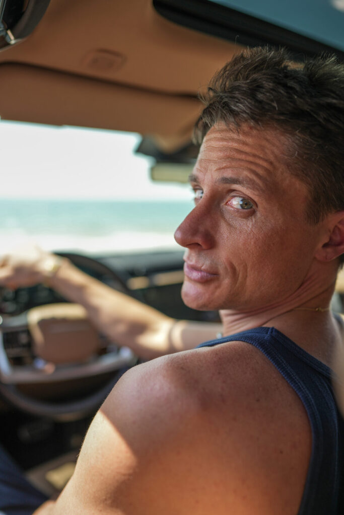 Mann mit energischem Blick dreht sich im Auto um, bereit zur Bewegung – Human Design, manifestierender Generator, Startenergie spürbar