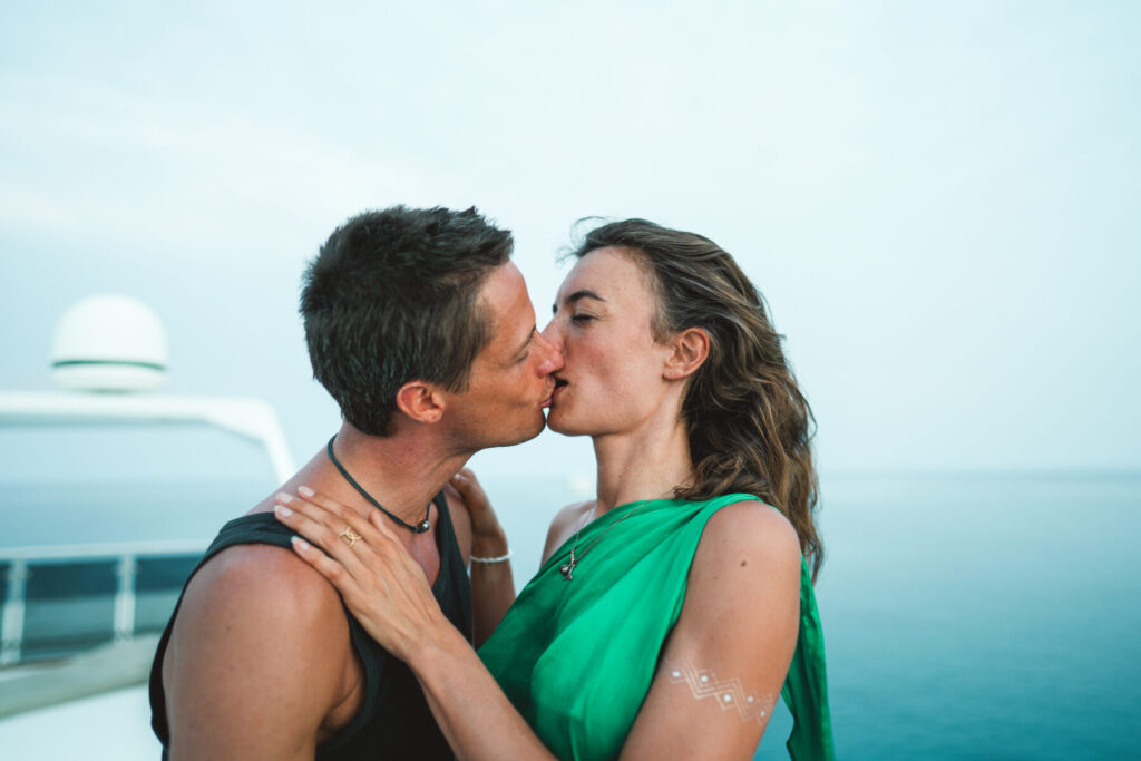 Gemeinsame Lebenskreation: Paar küsst sich am Meer und spiegelt bewusste Erschaffung deines Lebens durch Liebe und Verbindung