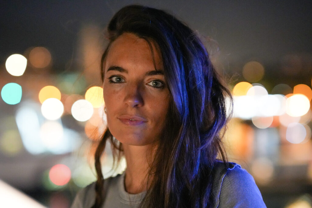 Klare Präsenz wählen – Frau im blauen Licht vor unscharfem Abendbokeh, fester Blick strahlt innere Ruhe trotz aufkommender Furcht.