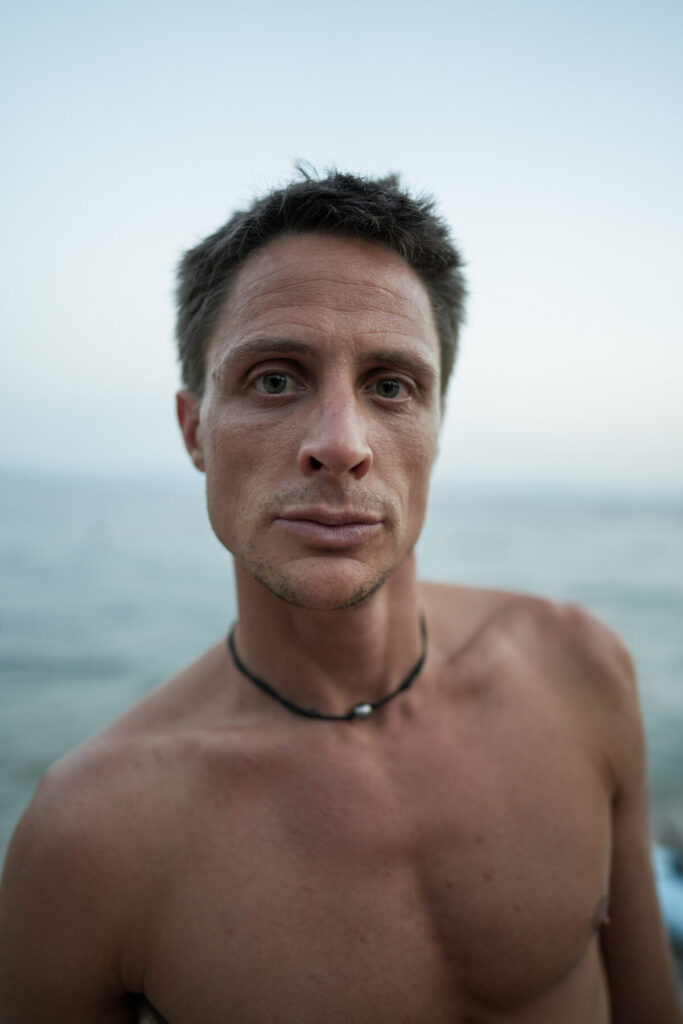 Herz öffnen – Nahaufnahme eines Mannes am Meer atmet tief, öffnet sein Herz und erschließt innere Balance.
