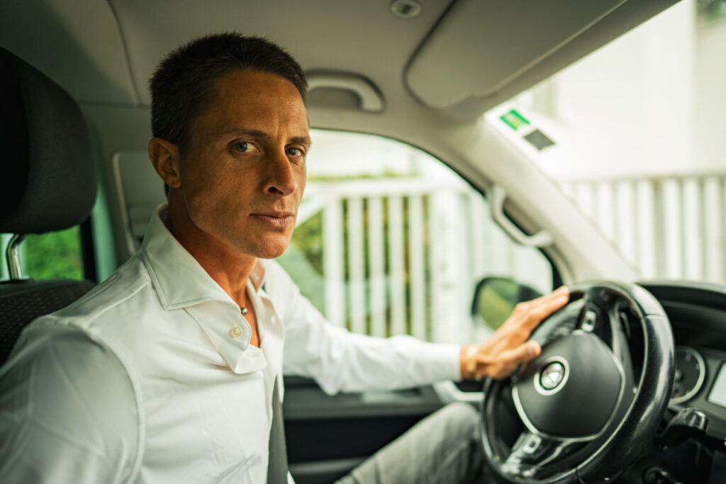 Führung zulassen – Mann im Auto am Steuer atmet tief ein und findet durch Breathwork Balance zwischen Geben und Empfangen.