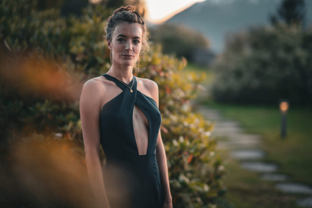 Druck kreativ lenken: Frau im eleganten schwarzen Kleid steht im Garten, atmet tief und hält den Druck sanft in Balance.