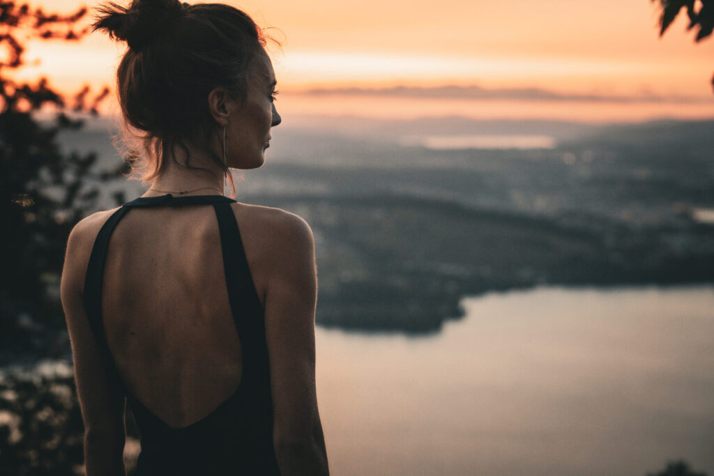 Rückblick und Ausblick – Frau steht über der Stadt im Abendlicht, weite Perspektive spiegelt Neubeginn, Vision und vollendete Entscheidung