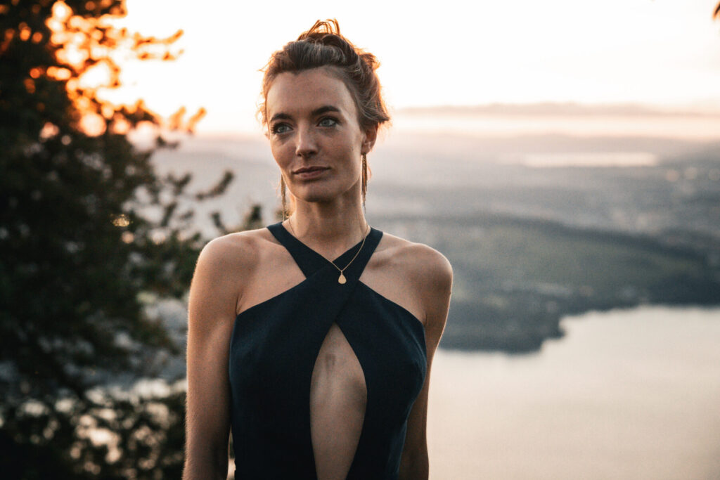 Innere Stärke und Würde – Frau steht auf Fels mit Blick über das Land, Sonnenlicht im Hintergrund, Haltung von Souveränität und stiller Tiefe