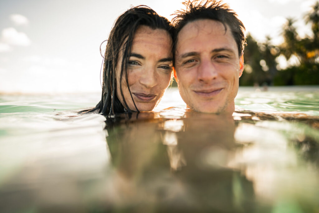 Ort voller Fülle ist Liebe im Element – Paar taucht gemeinsam im Wasser auf, Stirn an Stirn, sanftes Licht, Nähe, Wärme, Verbundenheit