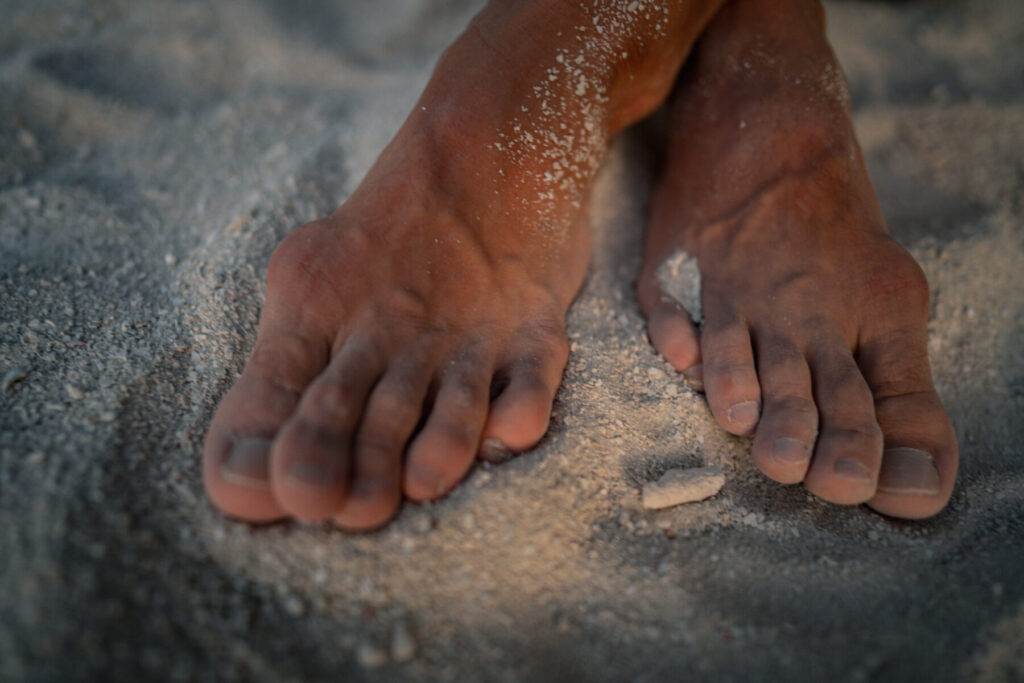 Bewusst wählen: Füße im Sand am Wasserrand spüren die erdende Fülle des Human Design aus der Tiefe.