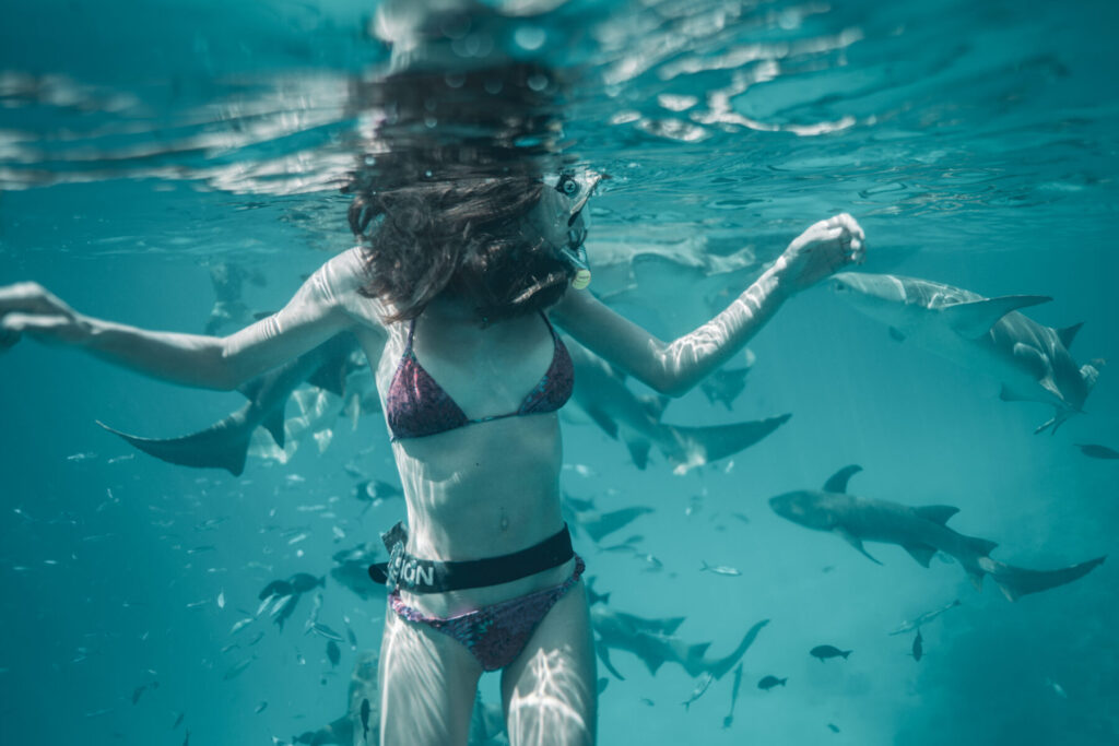 Frau schwimmt selbstbestimmt zwischen Fischen – Sinnbild für Freiheit, Impuls und das Navigieren eigener Wege im Ozean des Lebens