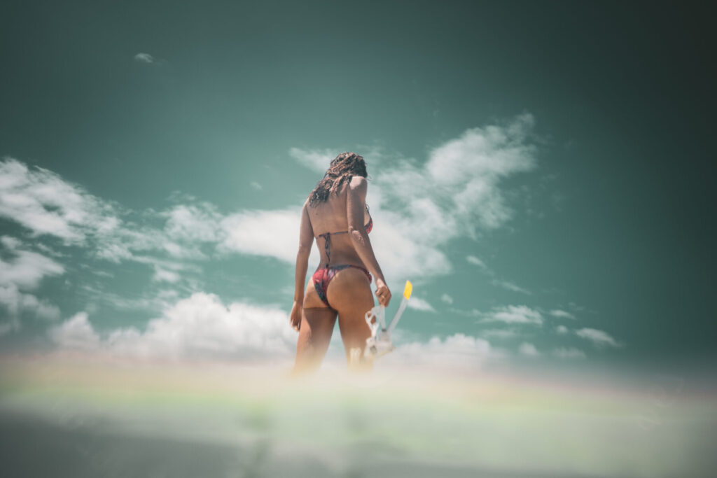 Wirksamkeit entfalten – Frau im Bikini am Strand mit Flossen öffnet Einladung im Human Design für den Projektor und lebt ihre Wahrheit.