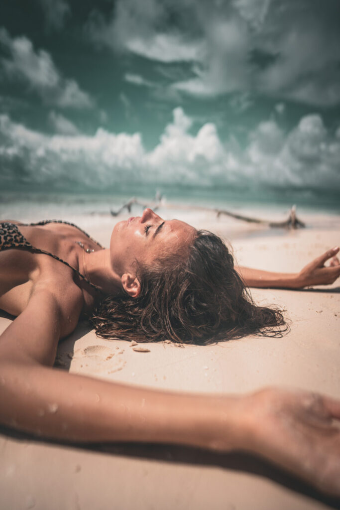Stress regulieren mit Atemarbeit – Frau liegt entspannt am Strand in der Sonne, voller Leichtigkeit, Atmung als Schlüssel für Ruhe und Gelöstheit.