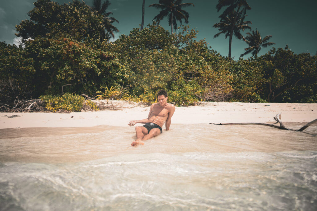 Own your Triggers: Mann am Strand sitzt entspannt im Sand und reflektiert Selbstverantwortung im Umgang mit Auslösern