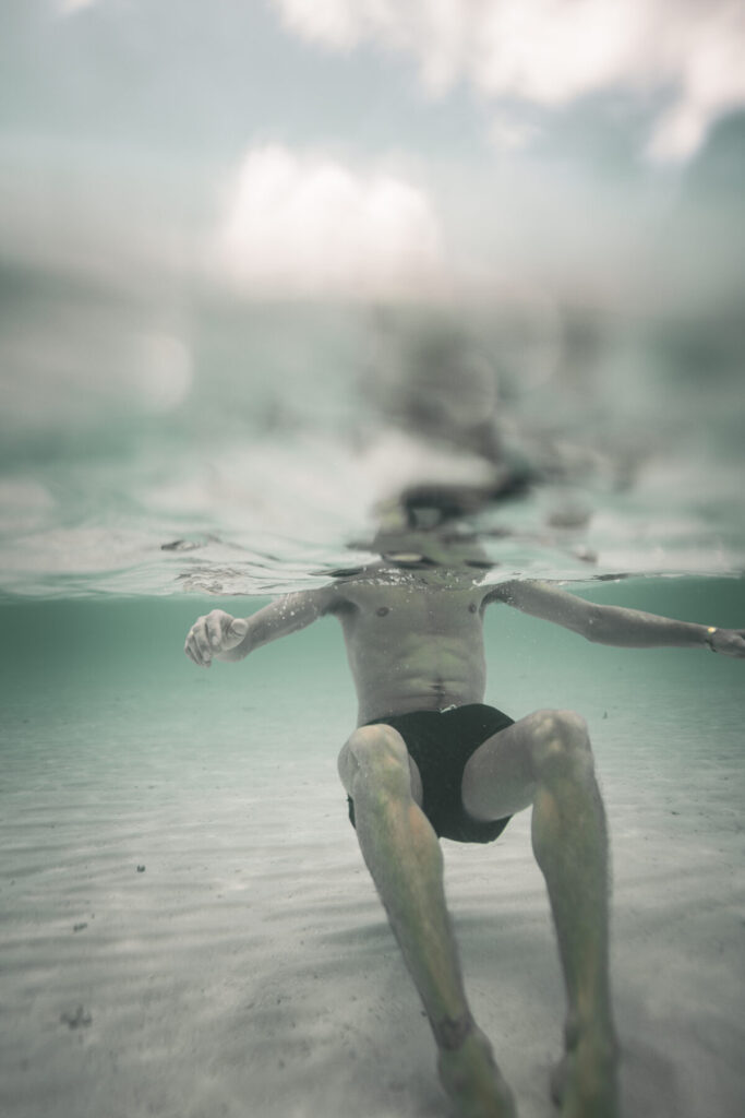 Loslassen im Blau – Mann treibt rücklings im Wasser und spürt „Hier wirst du frei“ in schwereloser Stille.