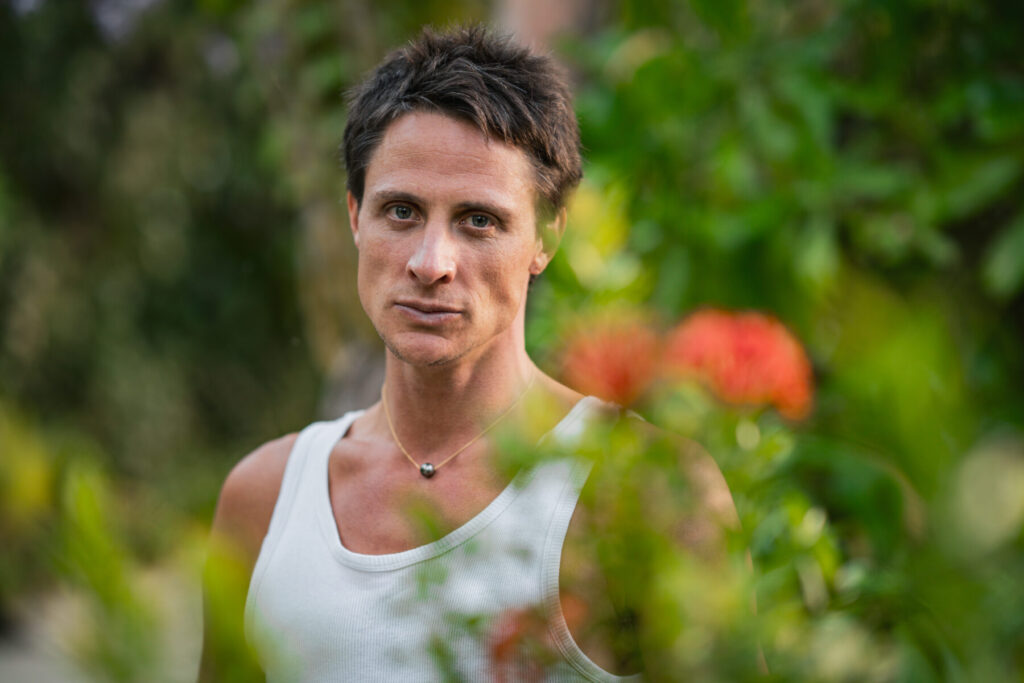 Botschaft tragen – Mann im Garten blickt fokussiert und verkörpert „We are Messengers of Eden“ in strahlender, reiner Präsenz.