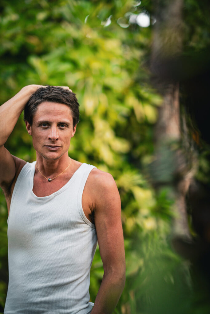 Projektor sein ist manipulieren – Mann in weißem Tanktop spürt klare Entscheidung in seiner Aura im Garten.
