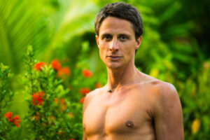 Balance finden – Mann im tropischen Garten steht shirtless, atmet bewusst und nutzt Breathwork für Herz-Kraft-Balance.