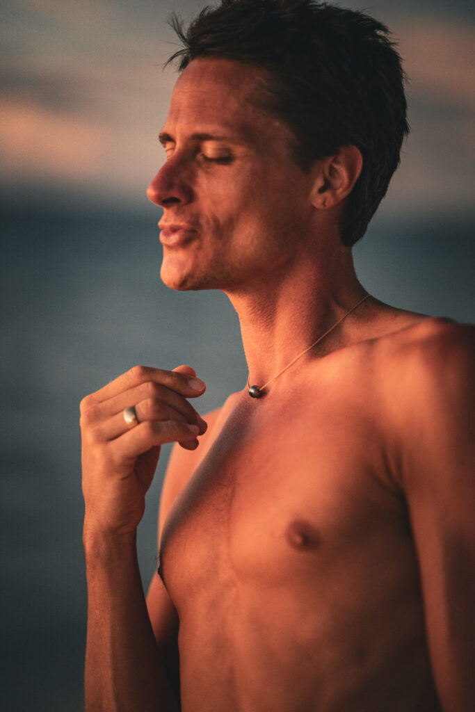 Die Geburt von Seas of Love – Mann berührt mit geschlossenen Augen sein Herz, Licht des Abends spiegelt Dankbarkeit und innere Weite