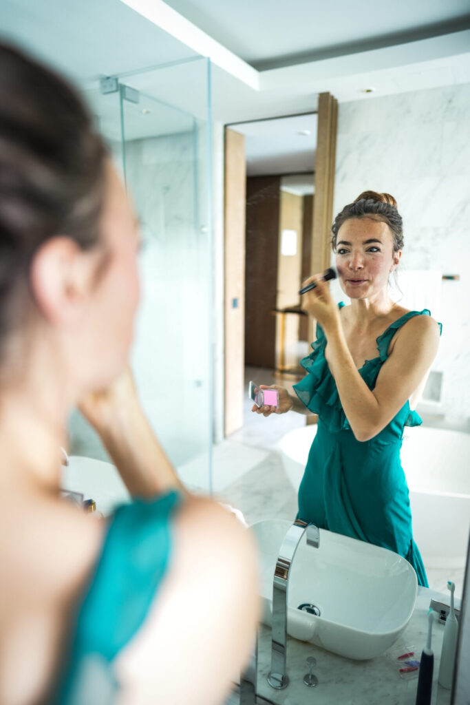 Human Design verkörpern – Frau im Spiegel trägt Make-up auf, zeigt bewusste Selbstfürsorge, Präsenz und Integration göttlicher Ordnung im Alltag