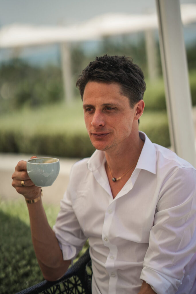 Innere Einheit beginnt im Moment – Mann im weißen Hemd trinkt Kaffee auf der Terrasse, ruhig, wach, kontemplative Stille