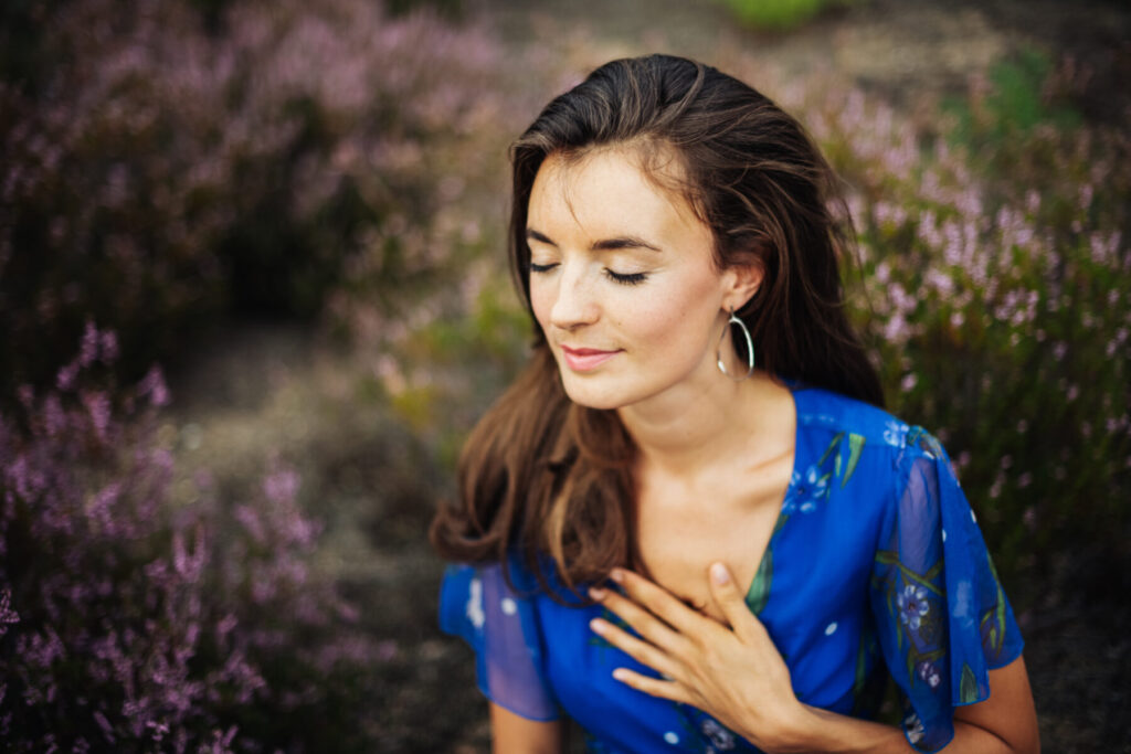 Herzverbindung als Schlüssel – Eine Frau in Meditation mit der Hand auf dem Herzen verkörpert Liebe als Ursprung der Fusion der Familie