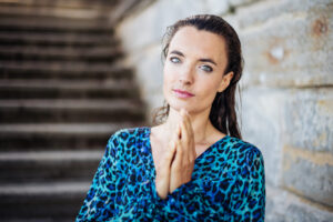 Breathwork online oder live – Frau mit gefalteten Händen in Präsenz vor Steintreppe, ruhiger Ausdruck, Transformation und Achtsamkeit spürbar.