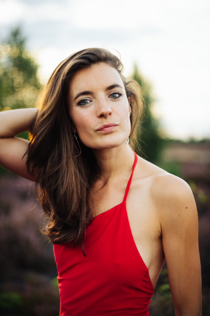 Reinheit verkörpern: Frau im roten Kleid blickt klar in die Kamera und strahlt spirituelle Klarheit und reine Aura aus.