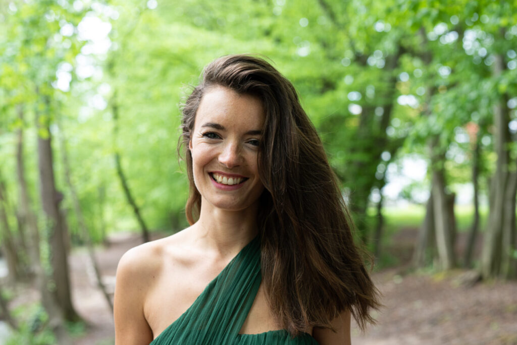 Channel des Loslassens – Frau im grünen Kleid lächelt im Wald, strahlt die sanfte Gabe des The Channel of Surrender aus und verbindet intuitiv Herzen.