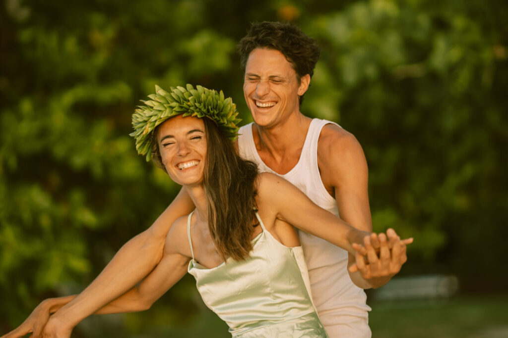 Herzensöffnung erleben: Paar lacht im Garten, strahlt paradiesische Freude und Liebe aus.