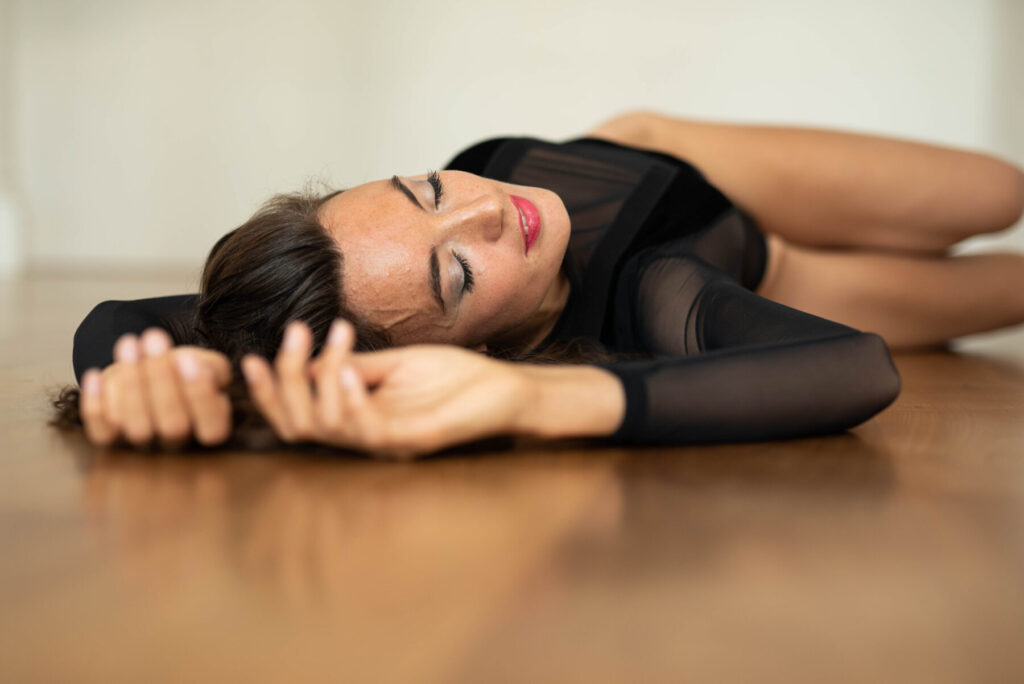 Strukturelles Trauma heilen: Frau liegt in eleganter Pose auf Holzfußboden und erlebt Befreiung durch Human Design als Weg aus dem Trauma