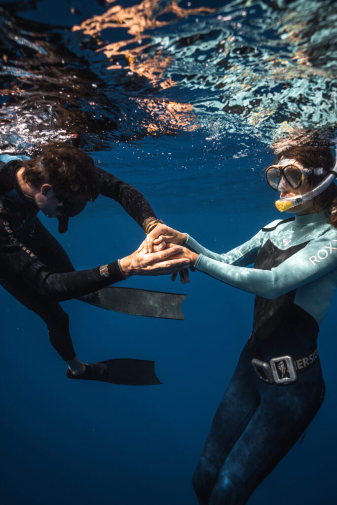 Bewusstes Sein – zwei Freediver berühren sich sanft unter Wasser, stehen für Verbindung in Stille, Vertrauen und Langsamkeit