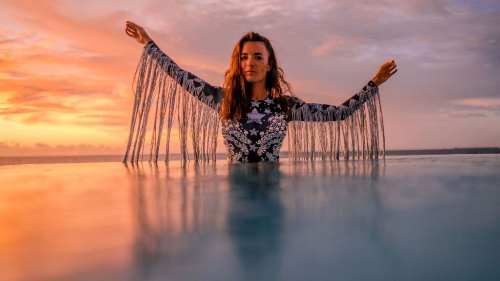 Frequenz des Meeres – Frau steht erhoben im Wasser bei Sonnenaufgang, Arme weit geöffnet, getragen von Stille, Kraft und Hingabe