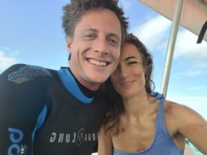 Schwingung im Feld – Paar lächelt in Taucherkleidung auf dem Boot, vereint in Leichtigkeit, Freude und hoher energetischer Verbindung