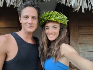 Liebe in Fülle – Paar mit Lei blickt strahlend in die Kamera und sendet „Grüsse aus Eden“ als Botschaft reiner Liebe und Fülle.