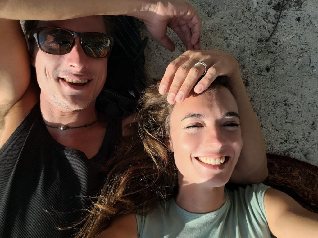 erst dürfen wir geben – zwei Menschen liegen lachend beieinander, Berührung und Freude im Moment, sichtbare Liebe, Leichtigkeit und gelebte Fülle